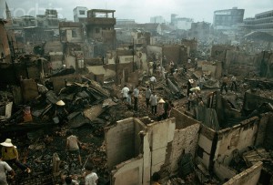 April 1975, Saigon, South Vietnam --- War victims walking through rubble after buildings were hit by a Vietcong missile in Saigon, South Vietnam. --- Image by © Nik Wheeler/CORBIS